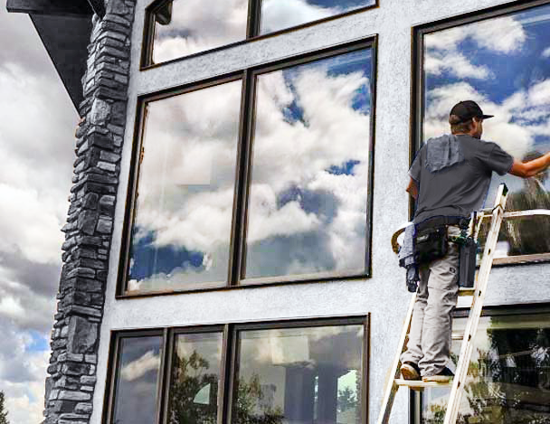 Window Cleaner crew member washing windows on ladder